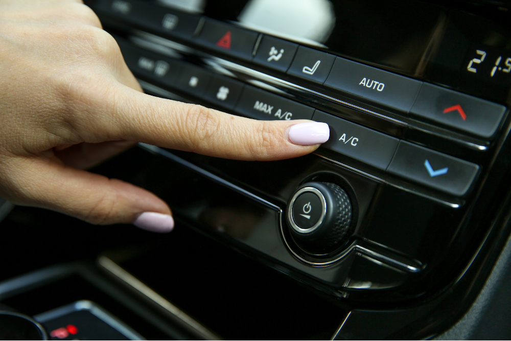 car a/c repair, Auto Repair & Service, Auto Body Repair & Auto Collision Repair in McAllen, Edinburg & Harlingen, TX. Close-up of a finger pressing the A/C button on a car's dashboard climate control panel, indicating HVAC troubleshooting.