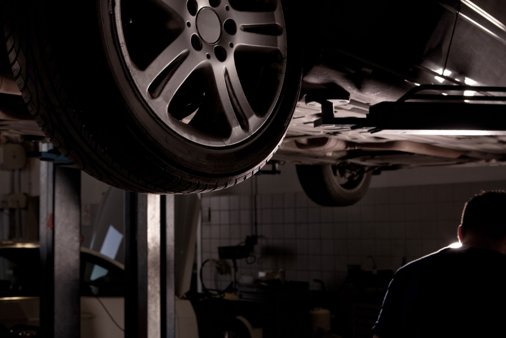 best auto repair shop, Auto Repair & Service, Auto Body Repair & Auto Collision Repair in McAllen, Edinburg & Harlingen, TX. Image of a vehicle lifted for inspection inside a dimly lit service bay, showcasing the shop’s dedication to thorough diagnostics and safe, professional automotive care.