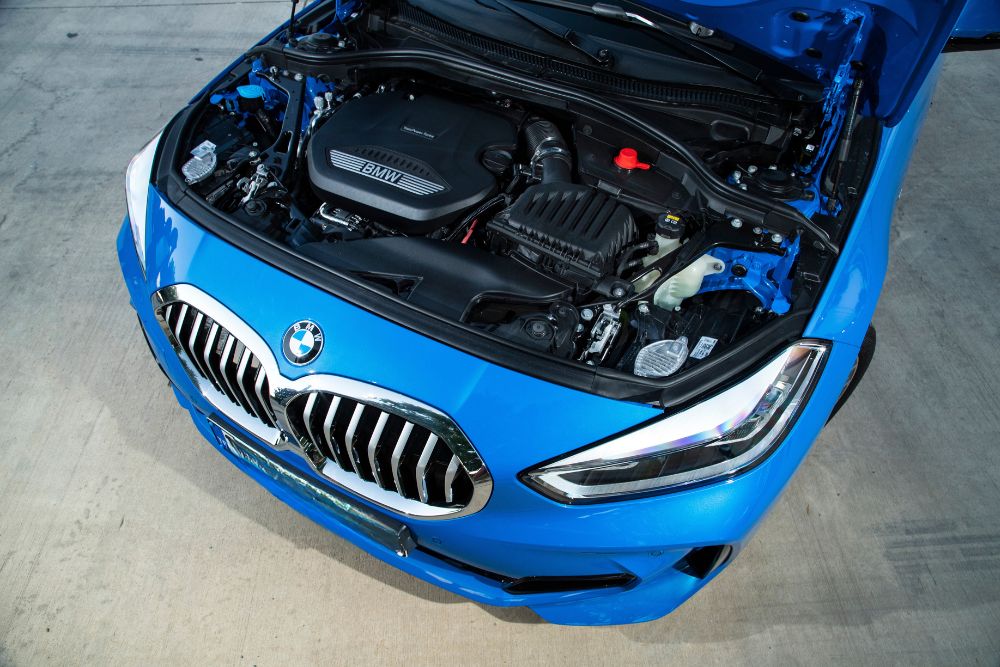 European, auto service in McAllen, TX by Premium Automotive. Blue BMW with hood open, highlighting precision engine care.