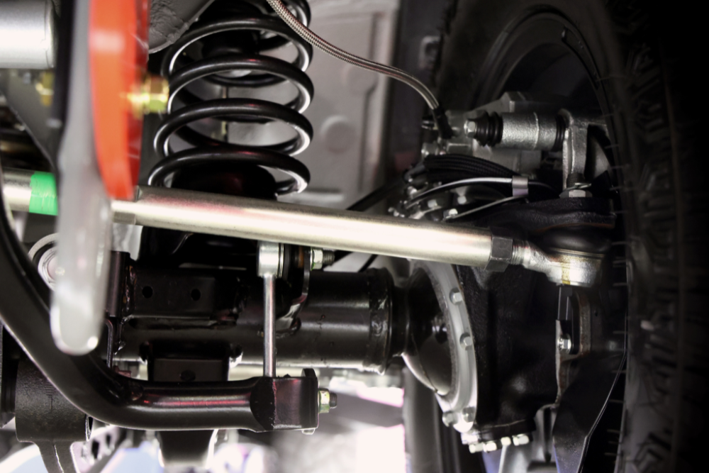 Steering & Suspension Repair in Edinburg, TX by Premium Automotive. Close-up view of a vehicle’s suspension system, showing the coil spring, shock absorber, and steering components.