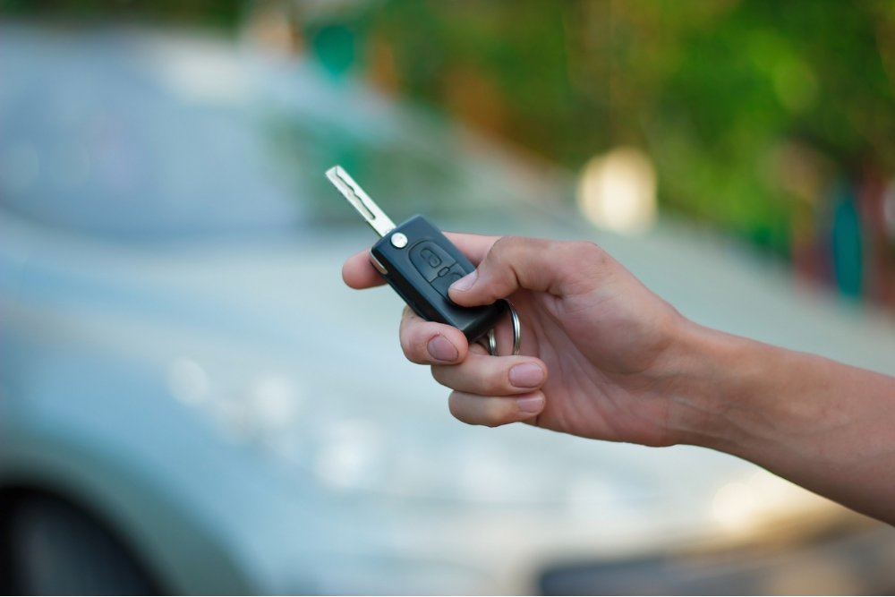 Key fob replacement in McAllen, TX by Premium Automotive. Image of a driver holding a car key fob near a vehicle, highlighting the shop’s commitment to secure, reliable key programming and vehicle safety.