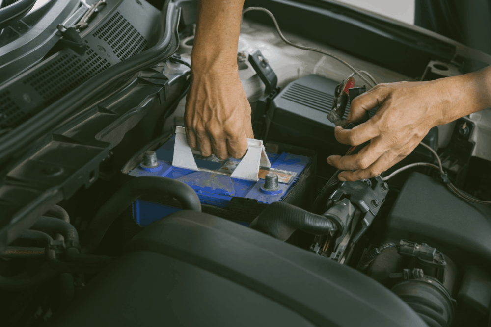 Car battery replacement and alternator repair in Edinburg, TX by Premium Automotive. Image of a technician disconnecting a vehicle battery terminal under the hood. Highlighting reliable starting power, charging system performance, and everyday driving safety.